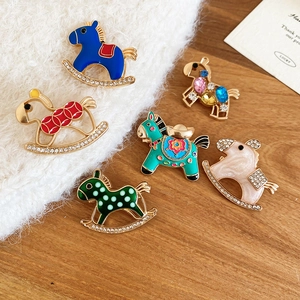 Detail showing six colorful enamel rocking horse brooches with gold-plated bases and crystals