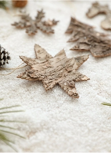 Detail view of natural wood Christmas ornaments in snowflake and star shapes on snow