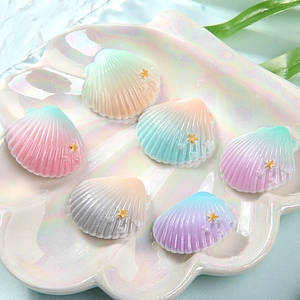 Colorful gradient resin seashell DIY charms with gold starfish accents on a pearl plate
