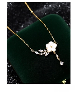 Detail of S925 silver necklace with white flower petal pendant on green velvet box