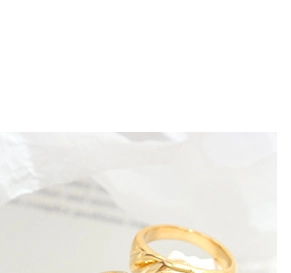 Close-up of a golden twisted knot ring with a minimalist polished finish on white texture