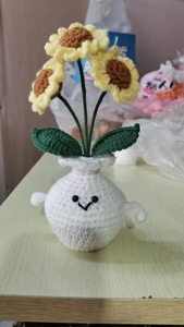 Macro shot of handmade crochet sunflower plant with a smiling face and cute arms