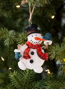 Close-up of a rustic textured snowman ornament with a red scarf hanging on a Christmas tree