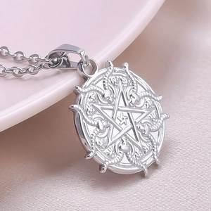 Macro view of silver goat pentagram pendant with snake engraving on pink silk fabric
