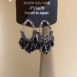 Detail of 925 silver hook on black beaded tassel earrings with crystal floral accents