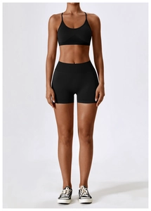 Detail of a black seamless yoga set with thin straps and high-waisted shorts on a model