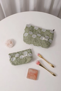 Detailed view of two-piece green cotton linen makeup bags with white floral embroidery