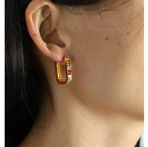 Close-up of gold rectangular hoop earrings with colorful zircon stones on model