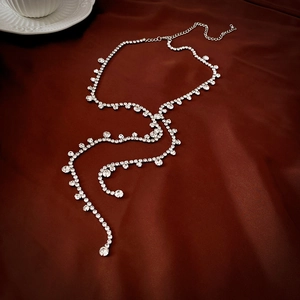 Detailed view of silver tassel necklace with rhinestones on dark satin background