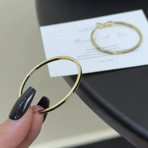 14k gold plated round hoop earrings held by hand featuring a vintage hollow design