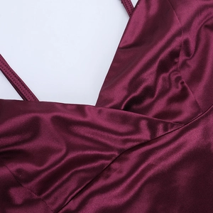 Detailed close-up of the burgundy satin fabric texture and cross V-neckline stitching