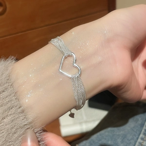 Macro detail of multilayer silver heart bracelet with delicate lace chain design