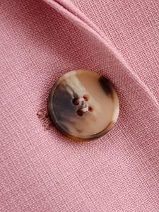 Detailed close-up of pink woven blazer fabric featuring a brown marbled button design
