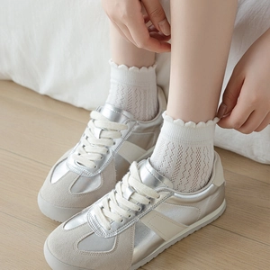 Chaussettes blanches en dentelle avec maille ajourée portées avec des baskets argentées