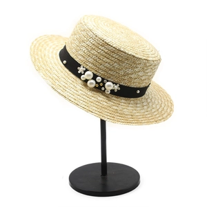 Handwoven straw boater hat with black ribbon and pearl flower trim on white background