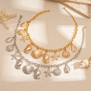 Metallic starfish and seashell pendant necklaces on a sandy summer beach background