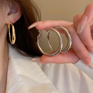 Detail of chunky gold and silver hoop earrings featuring high-polish mirror finish surface