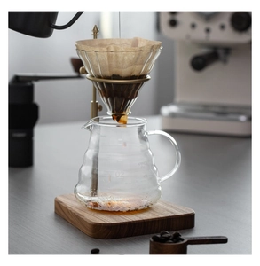 Macro shot of pour-over coffee set with brass stand, glass dripper and wooden base
