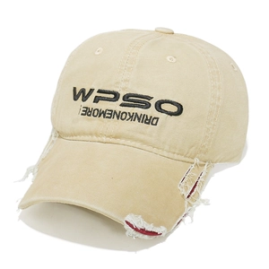 Close-up of distressed khaki canvas baseball cap with embroidery and frayed hole details