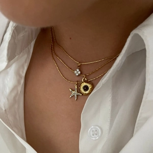 Three-layer gold stainless steel necklace with clover, sunburst disc, and starfish pendants