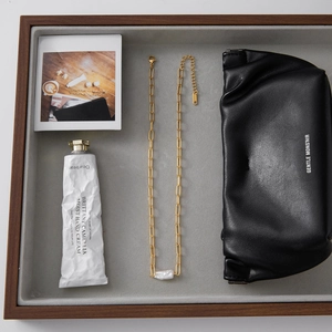 Detail van de gouden paperclip ketting met barokke parel op een grijs fluwelen dienblad