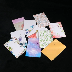 Various floral and artistic earring display cards scattered on a black background