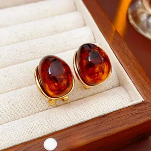 Close-up of vintage resin amber earrings in gold setting inside a wooden jewelry box