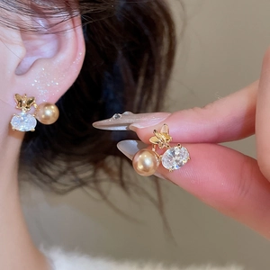 Dettaglio macro di orecchini a farfalla placcati oro 18K con zircone e perla pendente