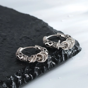 Retro men's hoop earrings with engraved patterns and charms on dark rock background