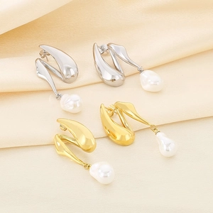 Detail of elegant gold and silver irregular pearl tassel earrings on beige silk fabric