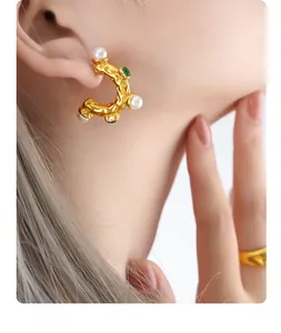 Détail de boucles d'oreilles vintage en forme de C avec perles et cristaux verts