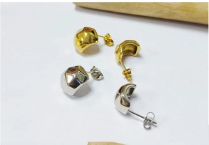Detail view of irregular geometric 18K gold and silver earrings with hammered texture