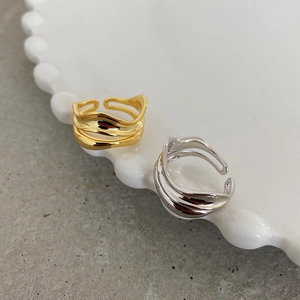 Detail of irregular wave layered rings in gold and silver on a white ceramic tray
