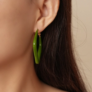 Primo piano di una modella che indossa un orecchino geometrico a goccia in resina verde