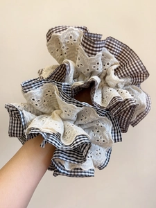 Macro view of oversized houndstooth and lace scrunchie with detailed layered fabric texture