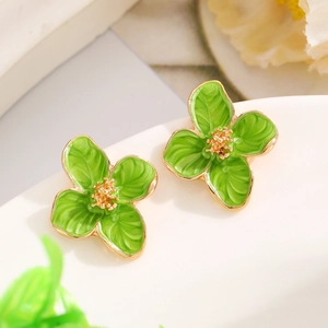 Macro detail of green enamel flower earrings with golden stamen and petal textures