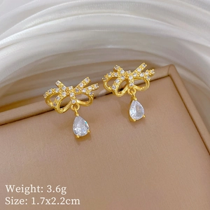 Close-up of gold butterfly stud earrings with zircon inlay and teardrop pendant