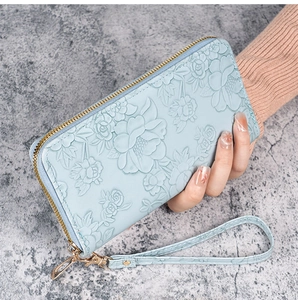 Macro shot of light blue long zipper wallet featuring elegant 3D floral embossing
