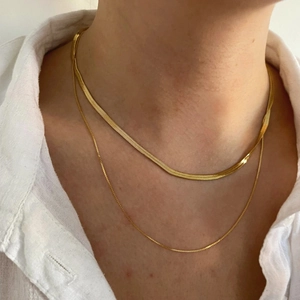 Gros plan d'un collier double rang avec chaîne serpent en or 18K sur le cou d'une femme