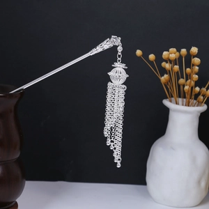 Detail of silver hair stick with hollowed flower sphere and delicate dangling metal tassels