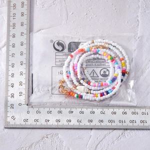 Vue détaillée du collier de perles avec pendentif coquillage et règle de mesure