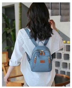 Modern nylon mini backpack in haze blue shown on a person to illustrate its compact size
