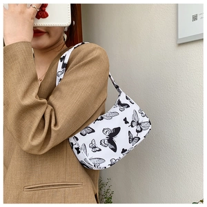 Close-up of stylish contrast underarm bag with black butterfly prints on white canvas