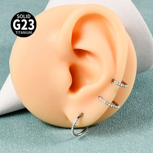 Macro detail of G23 titanium clicker rings with opal stones on a silicone ear model