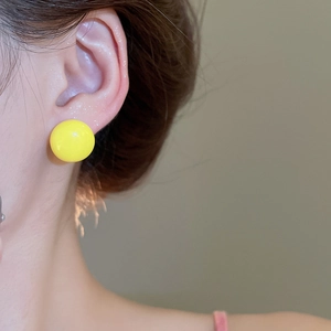 Close-up of model wearing bright yellow round resin ball stud earrings for women