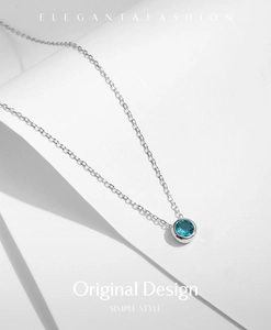 Macro shot of elegant S925 sterling silver necklace with blue gemstone pendant on white paper