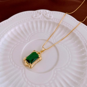 Detailed close-up of emerald green zircon pendant necklace on a vintage white ceramic plate