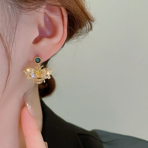 Close-up of zircon bee earring with yellow and green gemstones on a model ear