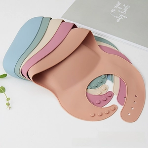 Close-up of five colorful silicone baby bibs with 3D food-catching pockets