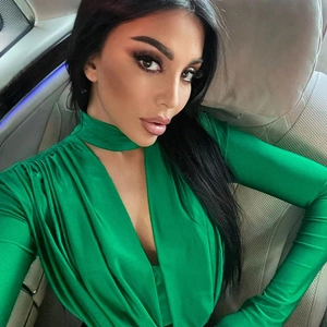 Detail of green satin V-neck bodysuit showing smooth fabric and decorative neck detail